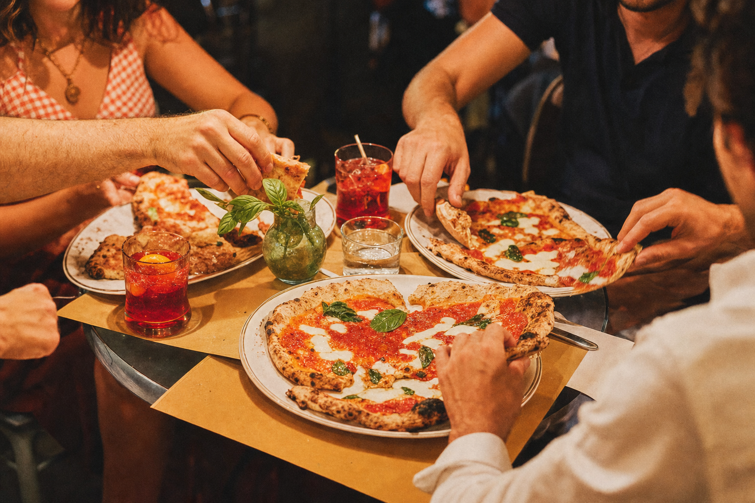 Amis partageant des pizzas et des verres d’aperitivo au restaurant